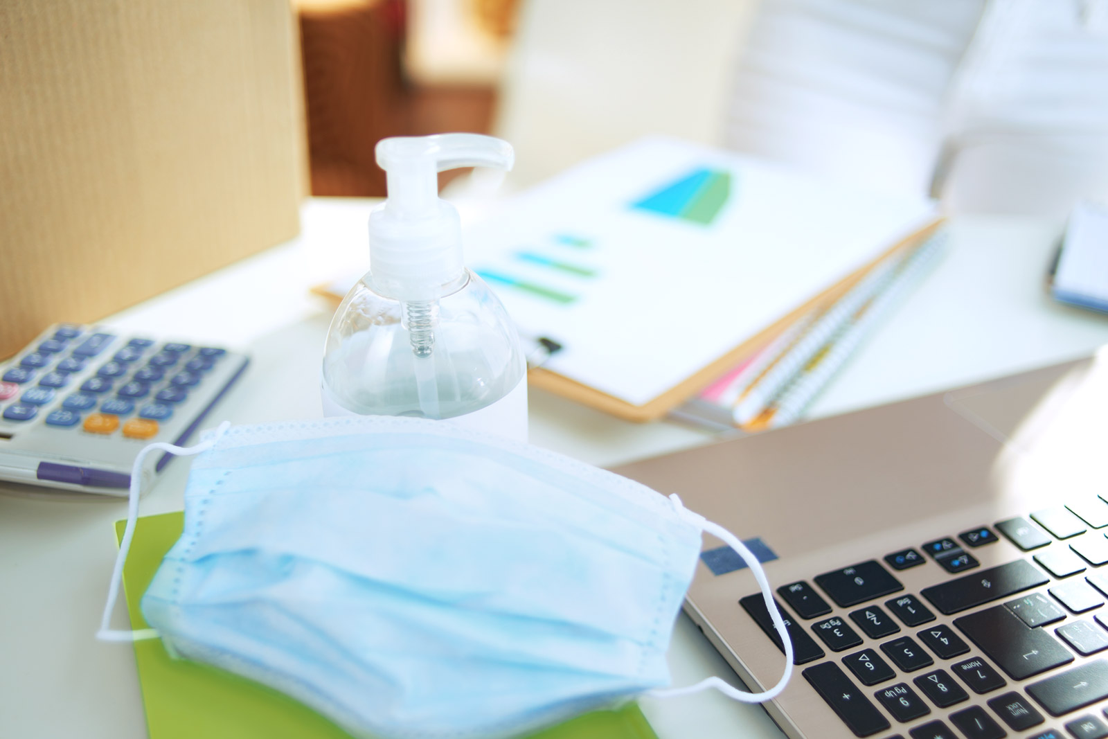 Arbeitsplatz mit Laptop Mundschutz und Desinfektionsmittel